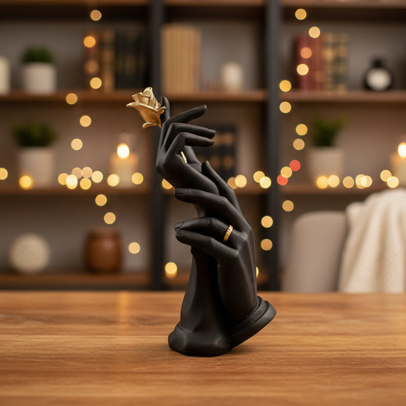 Escultura de manos negras con rosa dorada